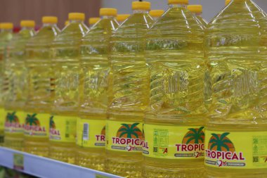 24 Ekim 2025 'te Balikpapan-Endonezya' da bir süpermarket rafında güzelce sergilenen, parlak sarı etiketli ve kapaklı, geniş, temiz, tropik marka pişirme yağı dolu bir sıra..