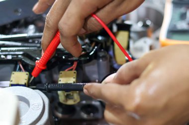 Tanısal test ve onarım sırasında otomatik aktarım valfinin kablo ve bobinlerini kontrol etmek için çoklu metre kullanan bir teknisyenin elleri.