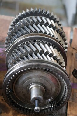 Parçalanmış iletim bileşenlerinin yakın çekimleri, bir atölyede incelemeye, onarmaya ya da yeniden monte etmeye hazır parlak metal dişli ve şaftları gösteriyor.