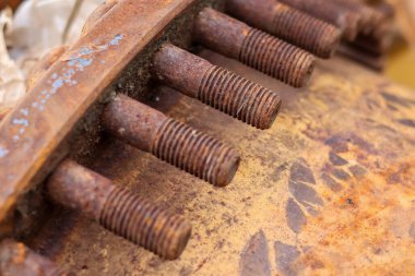 Makinenin yan tarafında paslanmış metal çiviler ve cıvatalar var. Yüzeyde aşınma ve bozulma var..