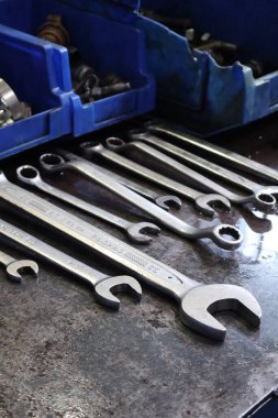 Balikpapan-Endonezya 7 Kasım 2025. Yıpranmış, yağlı metal bir tezgahın üzerinde mavi bir çöp tenekesi bulunan metrik anahtarların yakın çekimi..