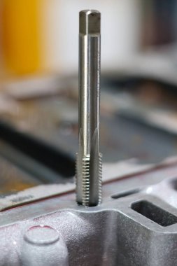 Metal bir otomotiv motoru veya emme manifoldunda delik açan yüksek hızlı bir çelik tıkırtı aracının yakın çekimi.