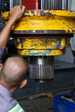 Bir teknisyen, büyük, yıpranmış bir endüstriyel bileşenden, ağır ekipman montajında ya da bakımında kritik bir adım olan hassas bacayı yakından inceler..