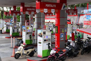 Balikpapan-Endonezya 11 Kasım 2025 Yakıt dağıtıcıları ve pompaları, Pertamina marka ürünler Pertalite ve Dexlite, Endonezya 'nın hareketli bir benzin istasyonunda motosikletle.