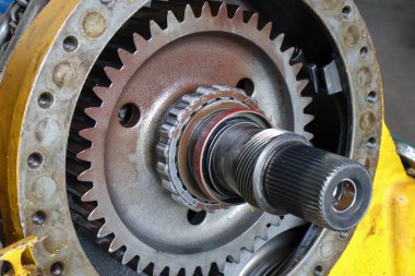 Ağır makinelerin son sürüş dingil şaftı ve iç dişli halka bileşeninin yakın plan görüntüsü, sarı metalik kaplama üzerinde ince ayrıntılar ve cıvata deliklerini gösterir.