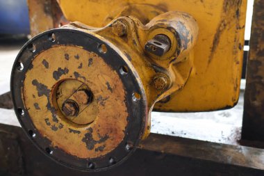 Yıpranmış, kirli çıkış kaplamasının ve ağır makinelerin son sürüş kaplamasının yakından görüntüsü, sürgülü delikler ve endüstriyel bir ortamda kırsal sarı boya kaplaması.