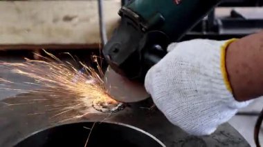 Metal bir yüzeyde beyaz eldiven takan bir işçinin yakın plan çekimi, üretim veya onarım ayarlarında parlak kıvılcımlar yaratır..