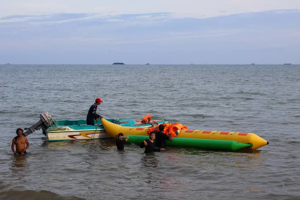 16 Kasım 2025 'te Balikpapan-Endonezya' da küçük motorlu bir tekne sakin denizde sarı ve yeşil şişirilebilir bir muz teknesinin yanına demirlemiş ve su sporu faaliyetlerine hazırdır..