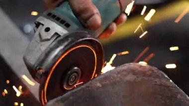 Açı öğütücüsünün yakın çekimi metali kesiyor, parlak sarı ve turuncu kıvılcımlar üretiyor, ağır üretimi ve metal işçiliğini sembolize ediyor.