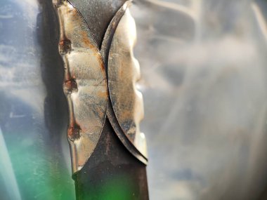 Koyu metal düz bir çubuğun ya da bıçağın yakın çekimi benzersiz, açık renkli, desenli metal kıskacı ya da sapı ile korunuyor, endüstriyel araç tasarımı, dokusu ve soyut mekanik detayı vurguluyor..