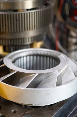 Karmaşık otomotiv ve endüstriyel mekaniği temsil eden bir atölye ortamında büyük bir halka teçhizatının yanına yerleştirilmiş bir tork dönüştürücü sustalı montaj..