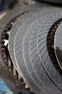 Yakın çekim desenli, kullanılan otomotiv debriyaj sürtünme plakaları (diskler) ve elmas desenli bir yüzey, güç iletimini sembolize eden mekanik sürtünme ve araç onarımı