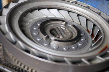 Metalik tork dönüştürücü itici ya da stator montajının ayrıntılı görüntüsü, merkezi eğrileri, türbin bıçaklarını ve karmaşık hidrolik güç iletimini ve onarımını temsil eden dış halkayı gösterir..