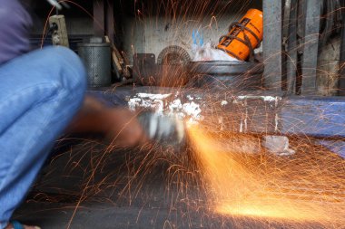 Parlak turuncu kıvılcımlar, el kamerası açılı öğütücüden inanılmaz bir şekilde uçar. Yavaş çekim yapan endüstriyel bir çekimde metali keser..