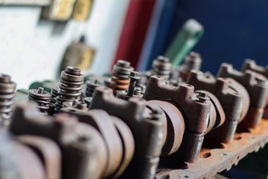 Parçalanmış, ağır paslanmış bir otomotiv motor silindirinin yakın çekimi. Bir tamircide mil yatakları, kapakçık yayları ve rockçı kolu montajlarını gösteriyor..