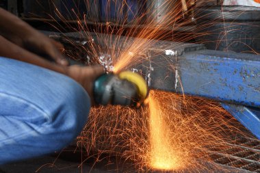 Parlak turuncu kıvılcımlar, el kamerası açılı öğütücüden inanılmaz bir şekilde uçar. Yavaş çekim yapan endüstriyel bir çekimde metali keser..