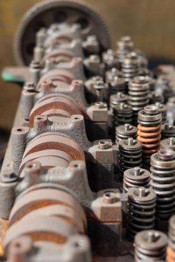 Parçalanmış, ağır paslanmış bir otomotiv motor silindirinin yakın çekimi. Bir tamircide mil yatakları, kapakçık yayları ve rockçı kolu montajlarını gösteriyor..