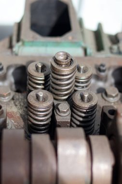 Parçalanmış, ağır paslanmış bir otomotiv motor silindirinin yakın çekimi. Bir tamircide mil yatakları, kapakçık yayları ve rockçı kolu montajlarını gösteriyor..