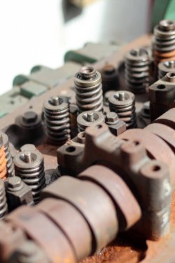 Parçalanmış, ağır paslanmış bir otomotiv motor silindirinin yakın çekimi. Bir tamircide mil yatakları, kapakçık yayları ve rockçı kolu montajlarını gösteriyor..