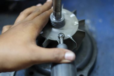 Turbo türbin tekerleği üzerinde hassas bir öğütme aracı kullanan bir teknisyenin, motor bileşenlerini dengelemek ve tamir etmek için profesyonel makine mühendisliğinin kapağını kapatın..