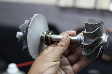 Kompresör ve türbin tekerlekleri, performans artırımı ve mekanik onarım için gerekli otomotiv motor bileşenleri olan türbülans şaftı tutan bir kişiyi kapatın.