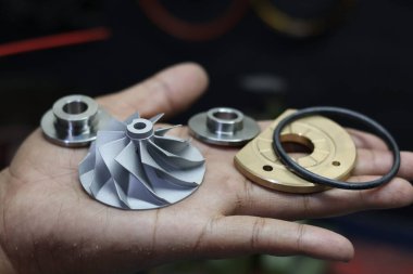 Bir elde tutulan kompresör tekerleği ve itme kuvveti de dahil olmak üzere çeşitli küçük turbo şarj yedek parçalarını kapat, otomotiv motor onarımı ve bakımı için temel bileşenler.