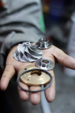 Bir elde tutulan kompresör tekerleği ve itme kuvveti de dahil olmak üzere çeşitli küçük turbo şarj yedek parçalarını kapat, otomotiv motor onarımı ve bakımı için temel bileşenler.