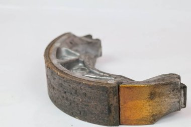 Beyaz arkaplanda desen ve metalik ayrıntıları gösteren aşınmış sürtünme pedleri olan motosiklet trampet fren ayakkabıları kullanılmış.