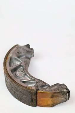 Beyaz arkaplanda desen ve metalik ayrıntıları gösteren aşınmış sürtünme pedleri olan motosiklet trampet fren ayakkabıları kullanılmış.