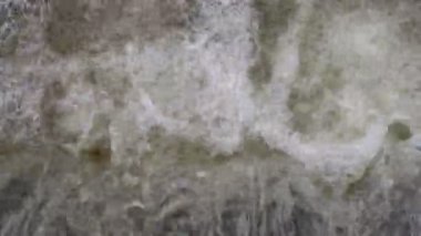 Kayalık bir çıkıntının üzerinden akan suyun üst görüntüsü doğal bir derede ya da nehirde beyaz köpük ve kabarcıklar oluşturur.