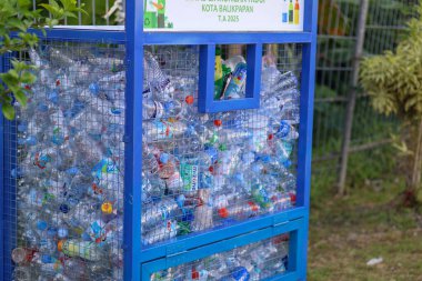 Balikpapan-Endonezya 29 Ocak 2026. Kullanılmış plastik su şişeleriyle dolu mavi metal geri dönüşüm kutusu. Açık bir kamu alanında atık yönetimi ve plastik koleksiyonu gösteren çevresel koruma kavramı.