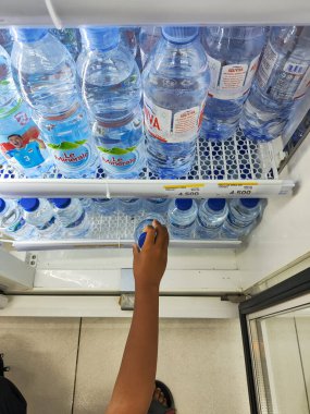Endonezya-Balikpapan-Endonezya 01 Şubat 2026 Bir kişinin eli bir süpermarket buzdolabının içinde soğutulmuş bir şişe maden suyuna uzanıyor, perakende alışveriş ve Endonezya 'da günlük su ihtiyacını gösteriyor.
