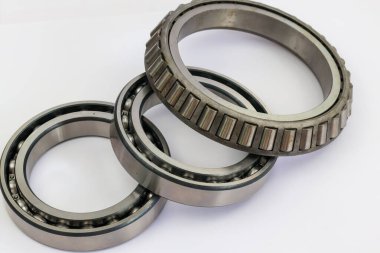 Otomotiv ve makine onarımı için beyaz arka plan profesyonel mekanik parçaların üzerine konmuş sanayi bilye ve konik rulman karşılaştırması.