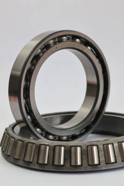 Otomotiv ve makine onarımı için beyaz arka plan profesyonel mekanik parçaların üzerine konmuş sanayi bilye ve konik rulman karşılaştırması.