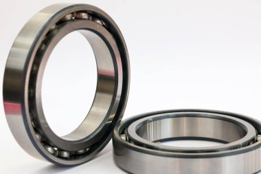 İki endüstriyel çelik bilye, bir ayakta duruyor ve bir tane de beyaz arka planda uzanıyor. Makineler ve otomotiv onarımı için profesyonel mekanik parça..