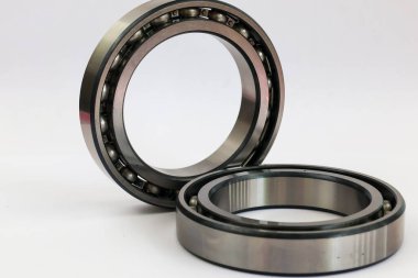 İki endüstriyel çelik bilye, bir ayakta duruyor ve bir tane de beyaz arka planda uzanıyor. Makineler ve otomotiv onarımı için profesyonel mekanik parça..