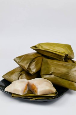 Geleneksel Endonezya muz keki Nagasari muz yapraklarına sarılı beyaz arka planda izole edilmiş bir tabakta servis ediliyor.