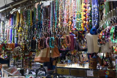 El yapımı etnik çantalar, boncuklu kolyeler ve parlak ışıkların altında sergilenen yerel el sanatları satan geleneksel bir Endonezya hediyelik eşya dükkanının içinde..