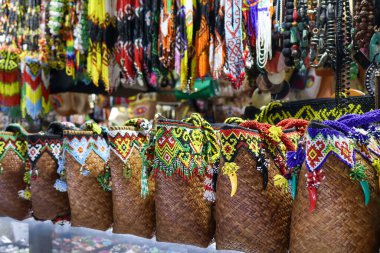 Yerel bir el işi hediyelik eşya pazarında gösterilen renkli etnik boncuklar, püsküller ve tılsımlarla süslenmiş geleneksel Endonezya el yapımı el yapımı çantaları..