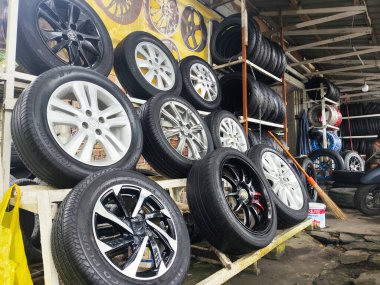 19 Şubat 2026 Balikpapan-Endonezya çeşitli araba lastikleri yerel bir otomotiv atölyesinde metal raflarda sergilenmektedir. Bu araç tekerlekleri düzgün bir şekilde satılığa çıkarılmış, nakliye bakımı için gerekli parçaları sağlıyorlar..