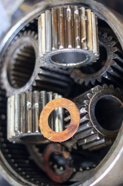 Makine bakımı için endüstriyel şanzıman montajında gezegen dişlilerinin ve paslı makinelerin yakın plan görüntüsü..