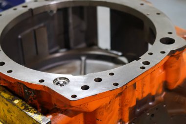 Ağır turuncu Allison şanzıman ana konutları bir atölyedeki ahşap tezgahta duruyor, endüstriyel araç vites kutusu bakımı için sağlam metalik döküm yapısı var..