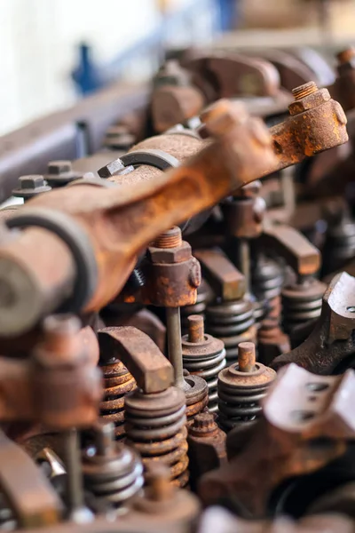 Mekanik bir atölyede rockçı kolları ve yayları olan paslı vintage motor valf treninin yakın çekimi.