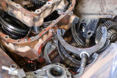 Mühendislik ve mekanik onarım temaları için bir tamir atölyesinde, vites değiştiren çatallar ve paslanmış metal parçaları da dahil olmak üzere parçalanmış otomotiv nakil bileşenlerinin yakın çekimi.