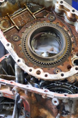 Hasarlı bir otomotiv nakil konutunun ve iç mekanik viteslerin ağır makine onarımı ve mühendislik bakım kavramlarını gösteren bir tamirhanedeki yakın çekimi.