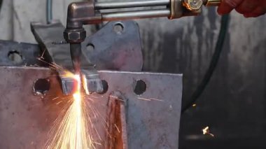 Teknisyenlerin eldiven giyip bir atölyede büyük bir endüstriyel teçhizatı kaldırmak için zincir çekilişine ağır çelik pranga takmalarına yakın durun. Elle donatma ve makine bakım süreci.