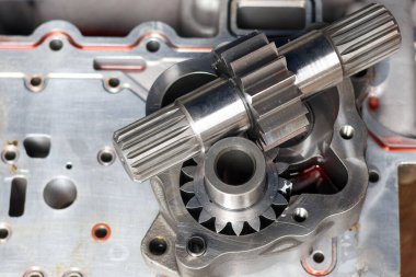 Parçalanmış çelik şanzıman dişlilerinin yüksek açılı görüntüsü ve metal tezgahların üzerine serpilmiş sürücü şaftları. Endüstriyel makine bakım ve onarım hizmeti için hassas mekanik motor parçaları.