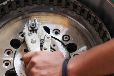 Tamir ya da bakım sırasında ağır bir makine endüstriyel bileşenine metal cıvata takmak için pense kullanan bir teknisyen elini kapat.