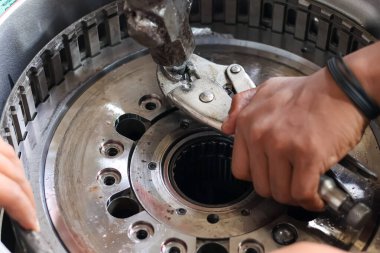 Tamir ya da bakım sırasında ağır bir makine endüstriyel bileşenine metal cıvata takmak için pense kullanan bir teknisyen elini kapat.