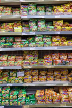 Balikpapan-Endonezya 14 Mart 2026 'da bir süpermarketteki perakende raflarda düzgünce istiflenmiş hazır erişte paketleri çeşitli aromalar ve modern bir mağaza koridorunda market alışverişi için renkli ambalajlar sergiliyor..